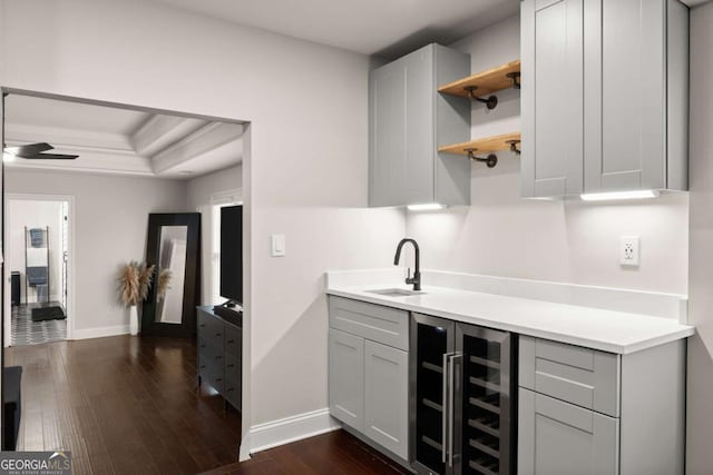 kitchen with sink, gray cabinetry, a tray ceiling, dark hardwood / wood-style flooring, and beverage cooler