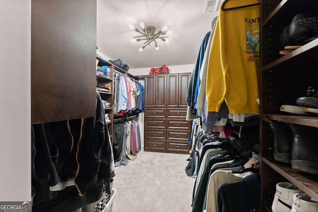 spacious closet with an inviting chandelier and light carpet