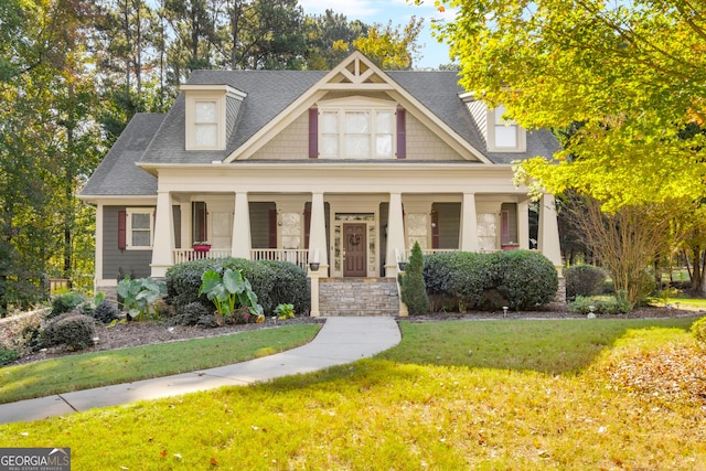 craftsman-style home featuring a porch, a shingled roof, and a front yard