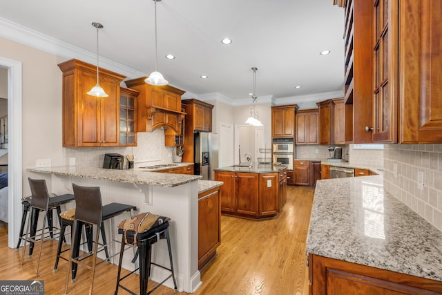 kitchen with light wood-type flooring, brown cabinetry, a sink, and dishwasher
