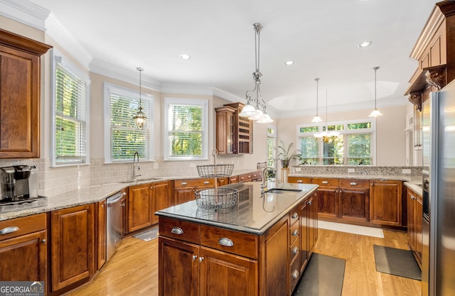 kitchen with appliances with stainless steel finishes, ornamental molding, light stone countertops, and brown cabinets