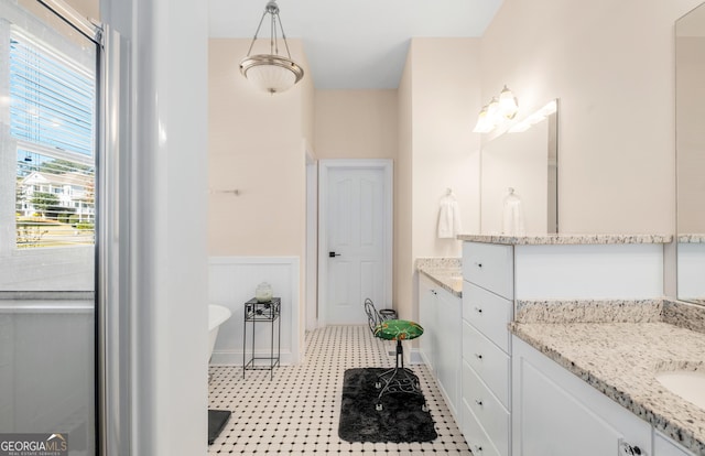 full bathroom with a freestanding tub, a healthy amount of sunlight, and a wainscoted wall