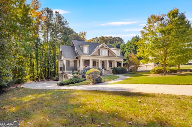 view of side of property with covered porch, an attached garage, driveway, and stone siding