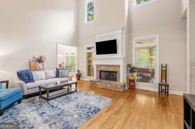 living area with a fireplace, wood finished floors, stairway, baseboards, and a high ceiling