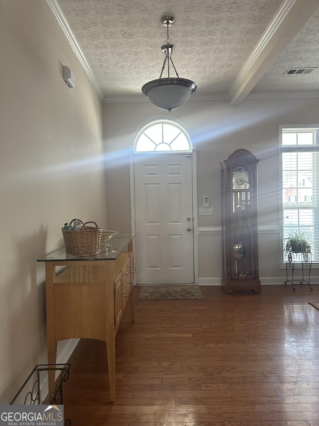 entrance foyer featuring dark wood-type flooring, a textured ceiling, and ornamental molding