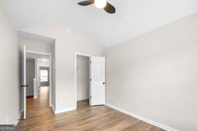 unfurnished bedroom featuring light hardwood / wood-style flooring, vaulted ceiling, a closet, and ceiling fan