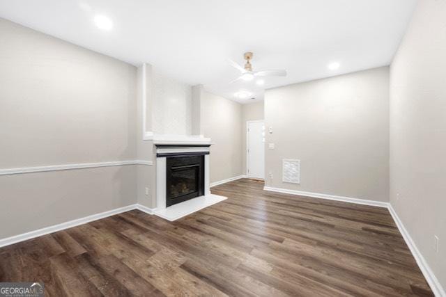 unfurnished living room featuring dark wood-type flooring and ceiling fan