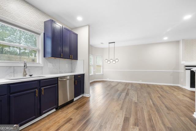 kitchen with pendant lighting, sink, wood-type flooring, decorative backsplash, and stainless steel dishwasher