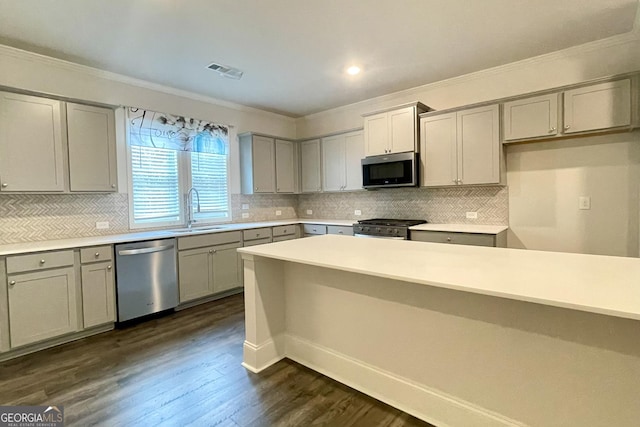 kitchen featuring dark wood-type flooring, ornamental molding, stainless steel appliances, and sink