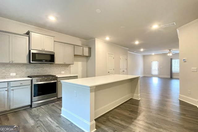 kitchen with gray cabinetry, tasteful backsplash, a center island, and appliances with stainless steel finishes