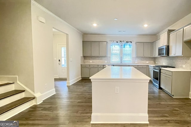 kitchen featuring gray cabinetry, a center island, dark hardwood / wood-style flooring, stainless steel appliances, and decorative backsplash