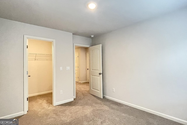 unfurnished bedroom with light carpet, a spacious closet, and a closet