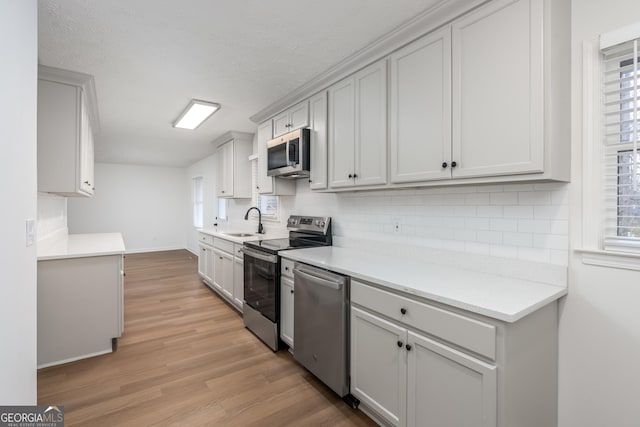 kitchen featuring sink, backsplash, stainless steel appliances, and light wood-type flooring