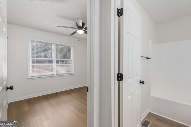 bathroom featuring wood-type flooring, a shower, ceiling fan, and a textured ceiling