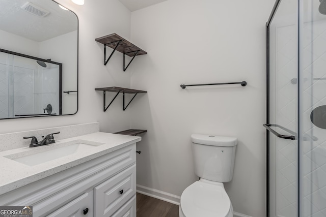 bathroom featuring vanity, hardwood / wood-style floors, an enclosed shower, and toilet