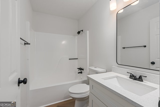 full bathroom featuring vanity, toilet,  shower combination, and a textured ceiling