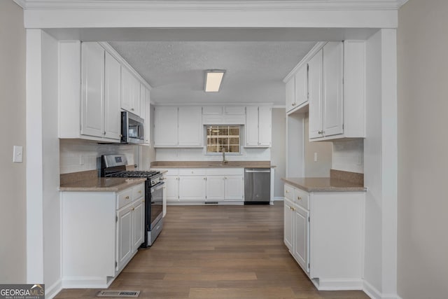 kitchen with dark hardwood / wood-style floors, tasteful backsplash, white cabinets, stainless steel appliances, and a textured ceiling