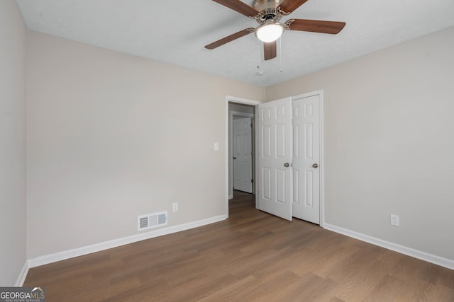 unfurnished bedroom with hardwood / wood-style flooring, a closet, and ceiling fan