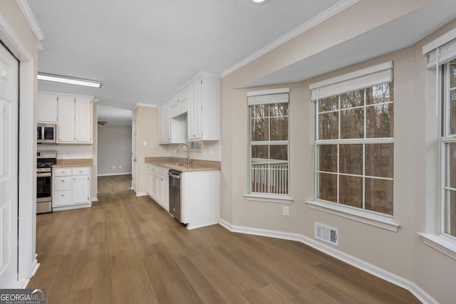 kitchen featuring dark hardwood / wood-style floors, white cabinetry, sink, stainless steel appliances, and a textured ceiling