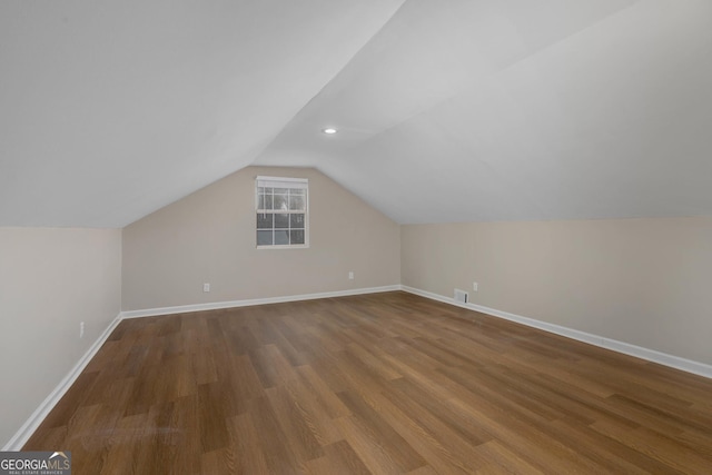 additional living space with hardwood / wood-style floors and vaulted ceiling