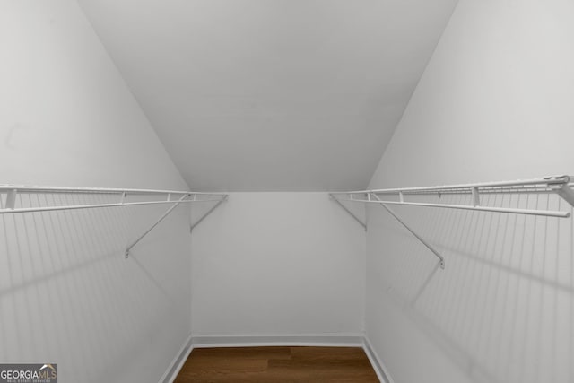 walk in closet featuring hardwood / wood-style flooring and vaulted ceiling