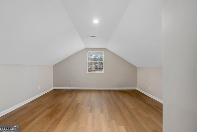 additional living space with vaulted ceiling and light hardwood / wood-style floors