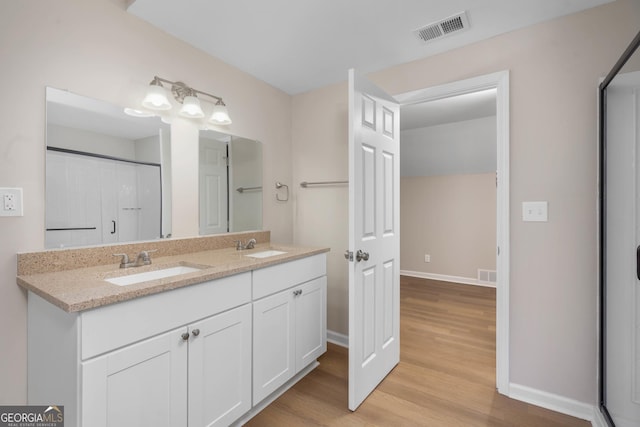 bathroom featuring wood-type flooring, vanity, and walk in shower