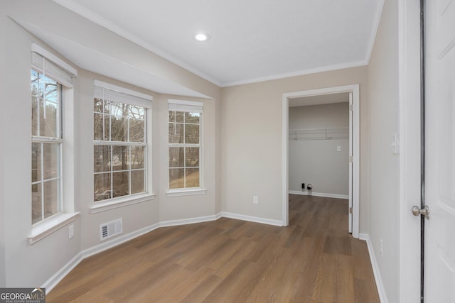 interior space with a closet, crown molding, a walk in closet, and dark hardwood / wood-style floors