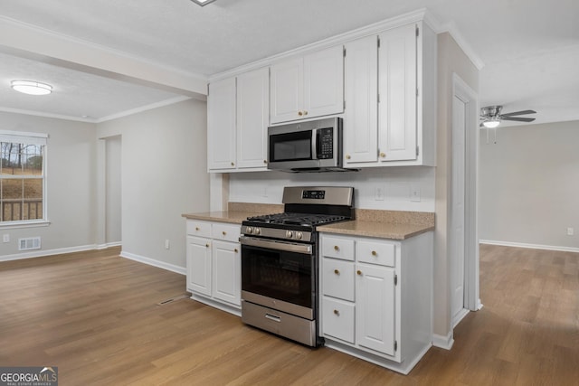 kitchen featuring stainless steel appliances, ornamental molding, white cabinets, and light hardwood / wood-style floors