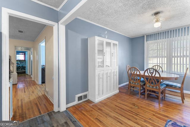 dining space with hardwood / wood-style flooring, crown molding, and a textured ceiling