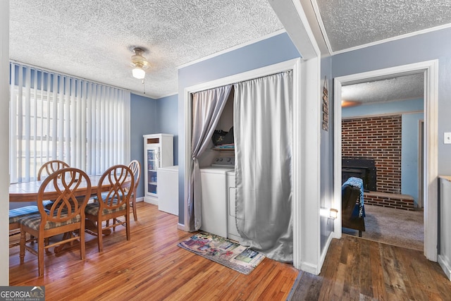 dining area with a fireplace, wood-type flooring, washer / clothes dryer, and a textured ceiling