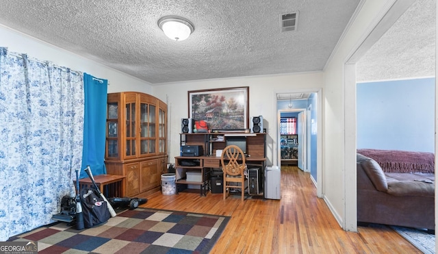 home office featuring hardwood / wood-style flooring, ornamental molding, and a textured ceiling