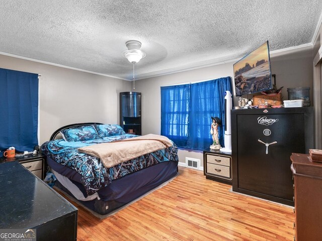 bedroom featuring crown molding, hardwood / wood-style floors, and a textured ceiling