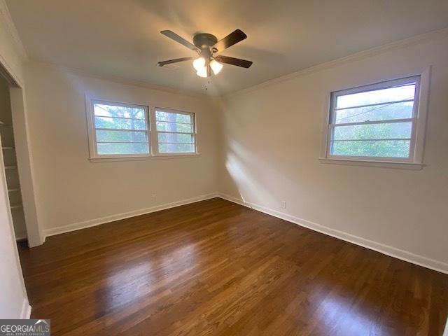 spare room featuring crown molding, ceiling fan, plenty of natural light, and dark hardwood / wood-style floors