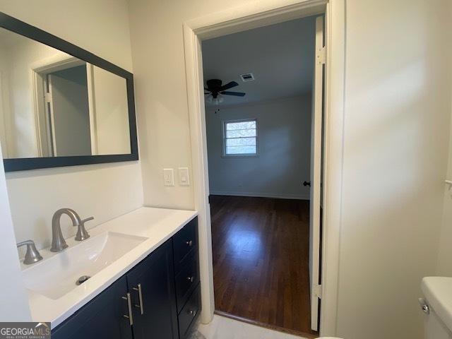 bathroom with ceiling fan, vanity, toilet, and hardwood / wood-style floors