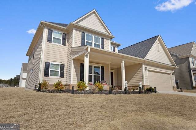 view of front of house featuring a garage, a front yard, and covered porch