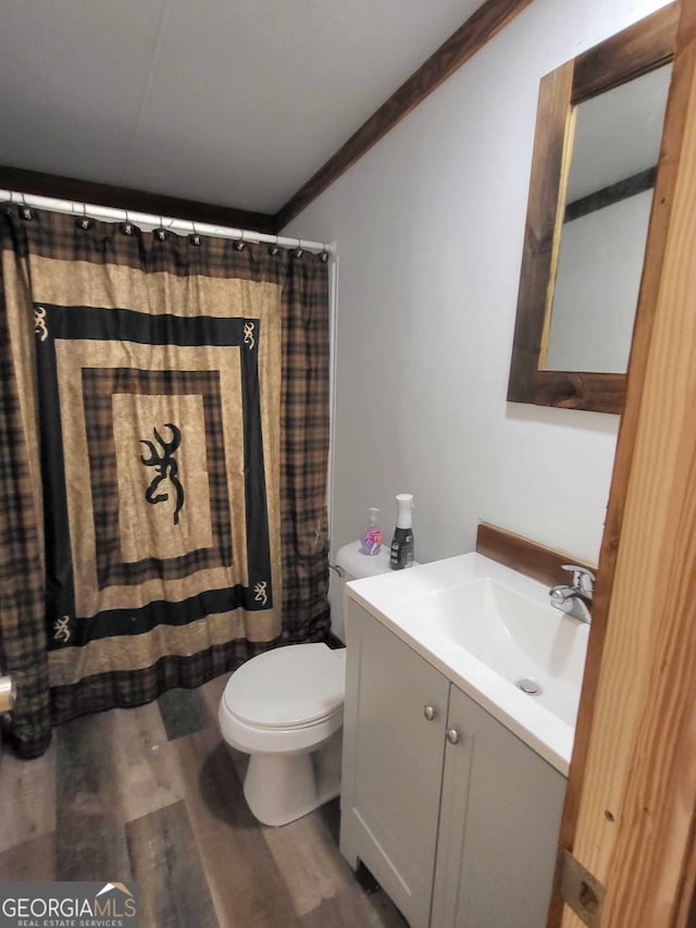 bathroom with wood-type flooring, ornamental molding, vanity, walk in shower, and toilet