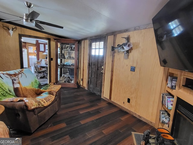 living room with dark hardwood / wood-style floors, ceiling fan, and wood walls