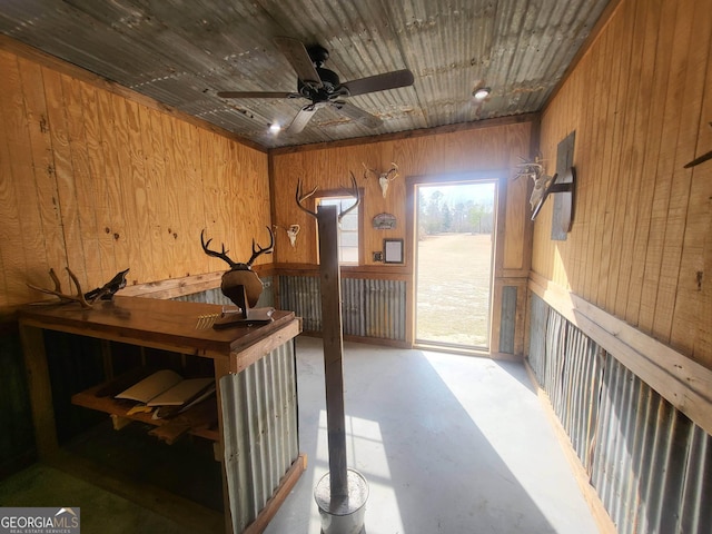 interior space featuring wood ceiling, ceiling fan, and wooden walls