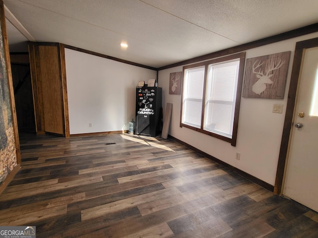 spare room featuring dark wood-type flooring and a textured ceiling