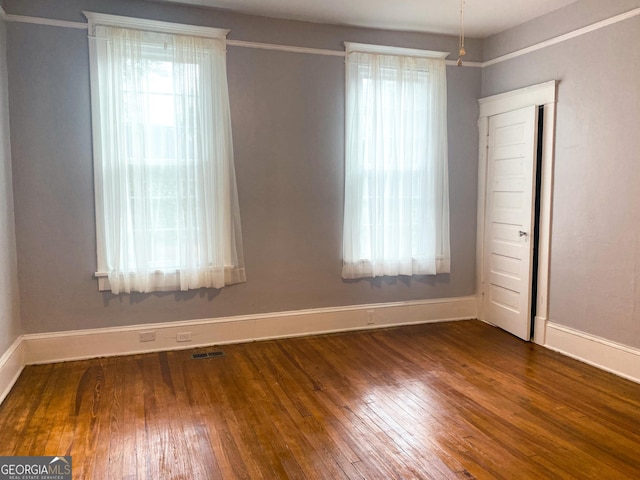 unfurnished room featuring dark wood-type flooring and a healthy amount of sunlight