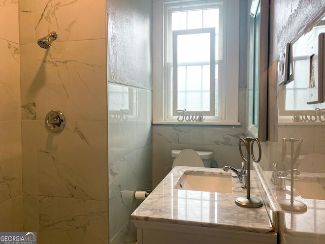 bathroom featuring tiled shower, vanity, toilet, and tile walls