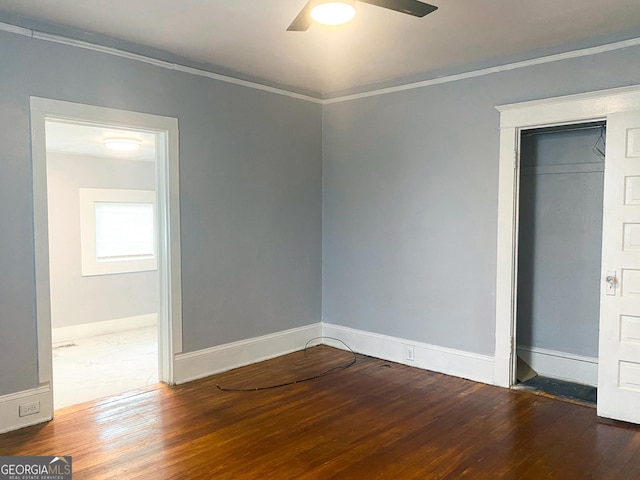 unfurnished bedroom with a closet, crown molding, dark hardwood / wood-style floors, and ceiling fan