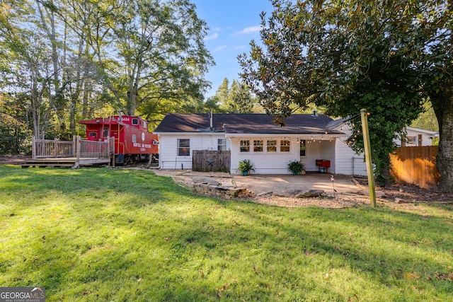 rear view of house featuring a garage, a lawn, and a deck