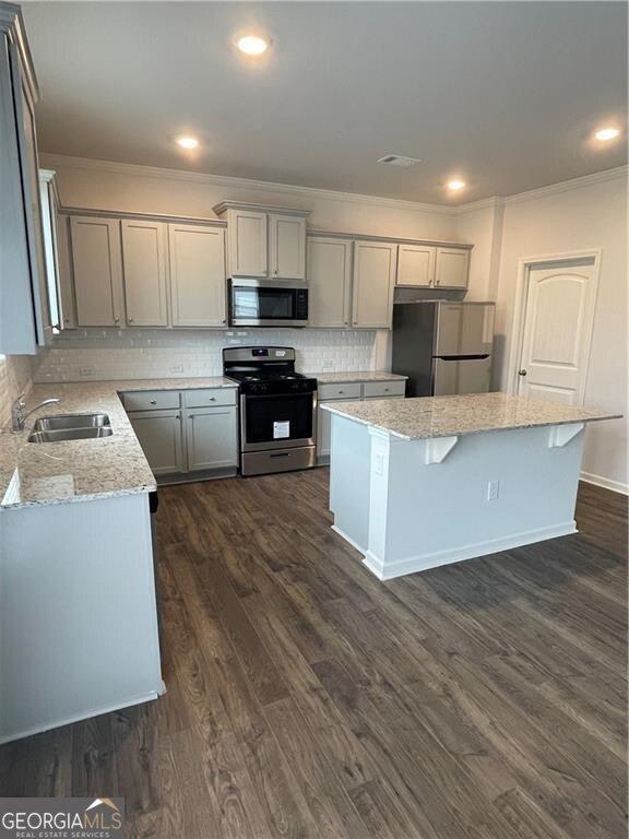 kitchen with appliances with stainless steel finishes, dark hardwood / wood-style floors, a center island, and gray cabinetry