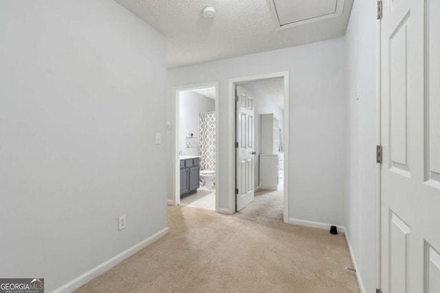 hallway featuring light carpet and a textured ceiling