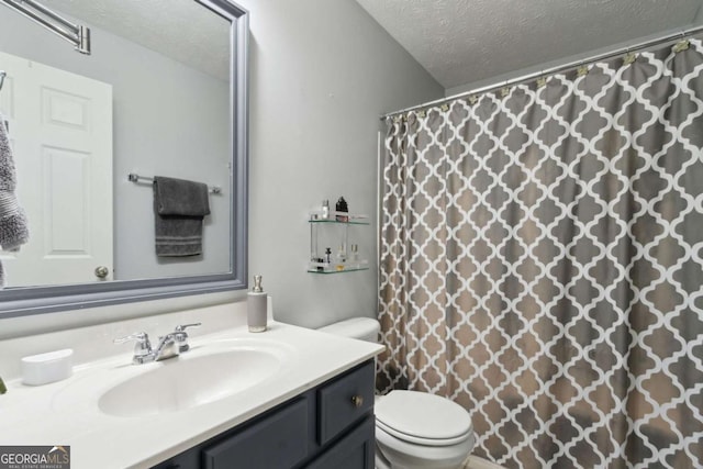 bathroom featuring walk in shower, vanity, toilet, and a textured ceiling