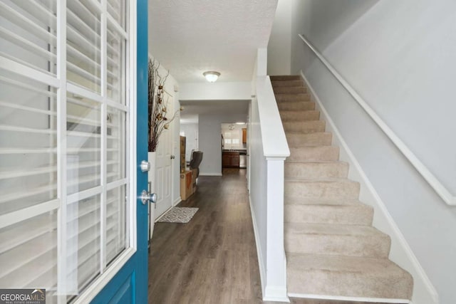 stairway with wood-type flooring and a textured ceiling