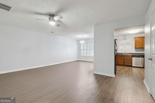 unfurnished room with hardwood / wood-style flooring, sink, a textured ceiling, and a wealth of natural light