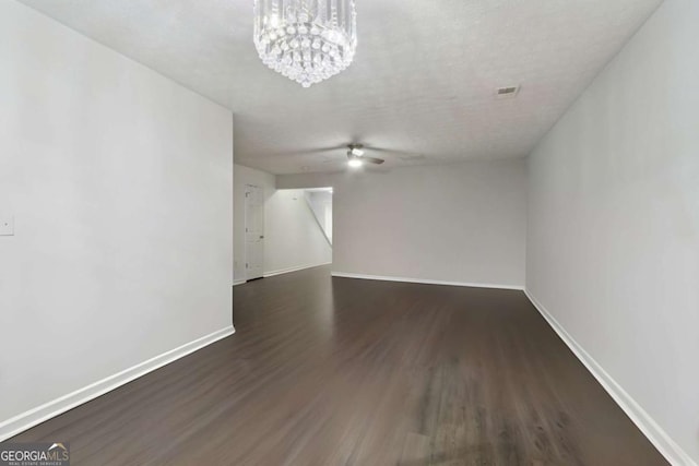 interior space with dark hardwood / wood-style floors, ceiling fan with notable chandelier, and a textured ceiling